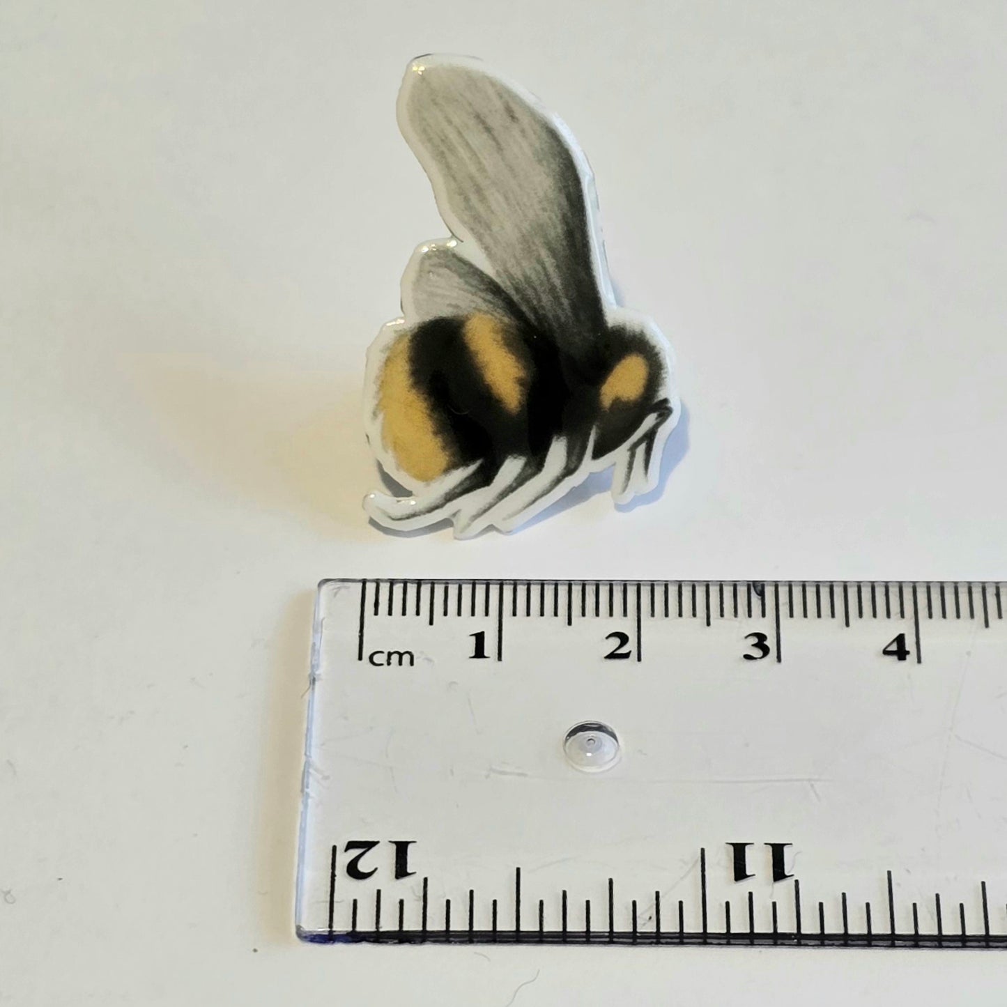 Handmade bumblebee badge pin shown with ruler for size reference