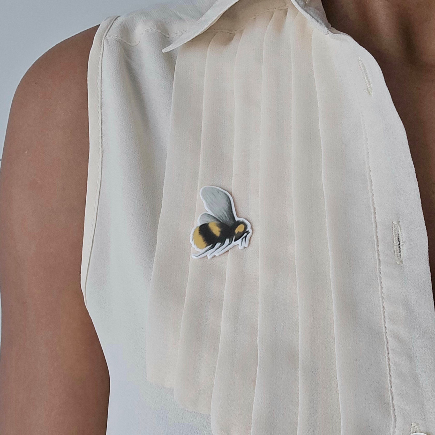 Bumblebee resin badge pin attached to a cream blouse