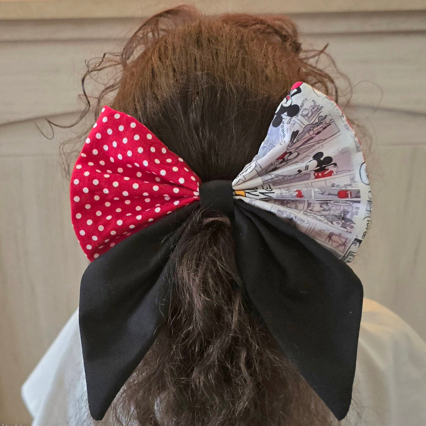 Large handmade patchwork hair bow with red polka dot fabric worn in curly hair
