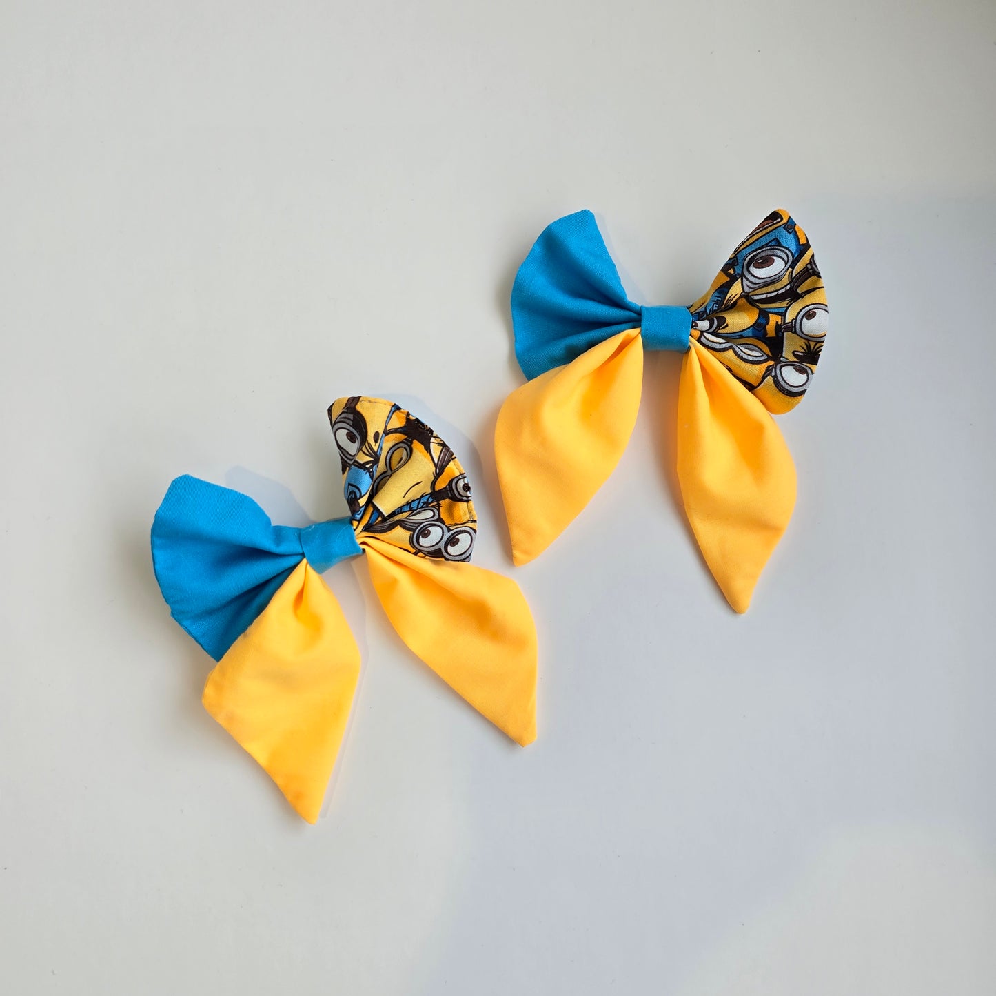 Two fabric bows with yellow and blue sections on a white background