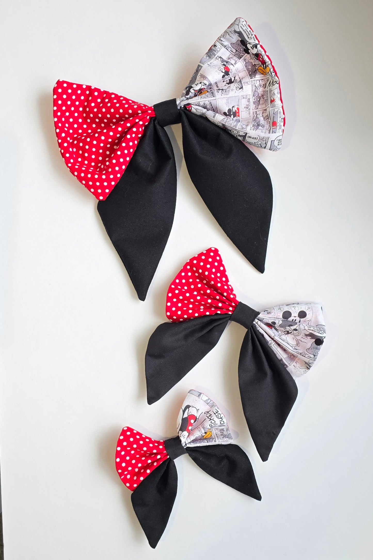 Handmade boutique hair bows with patchwork fabric panels and black tails in three different sizes
